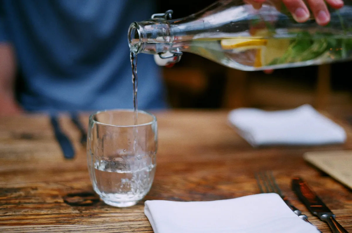 A glass of water beside water-rich fruits and vegetables