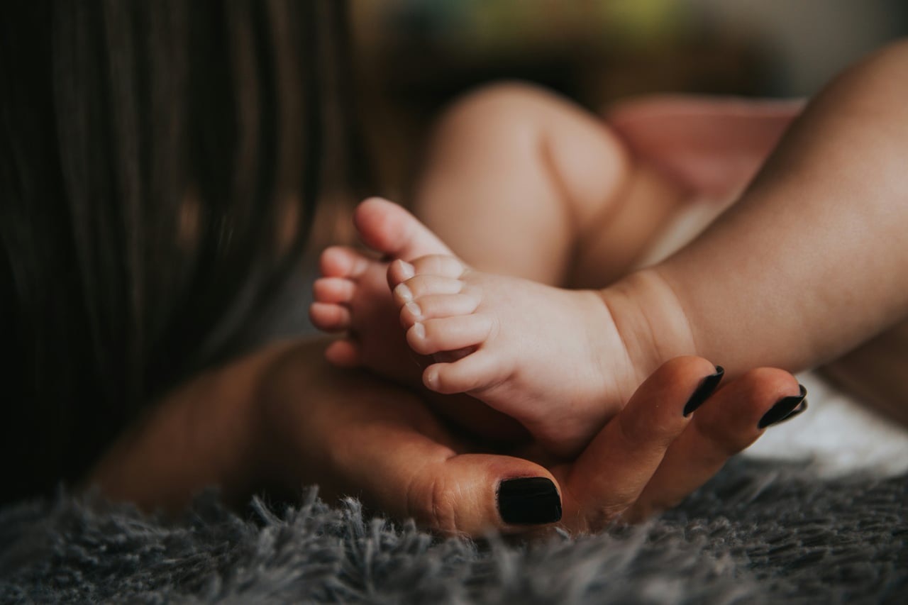 La main d'un parent tenant les pieds d'un bébé