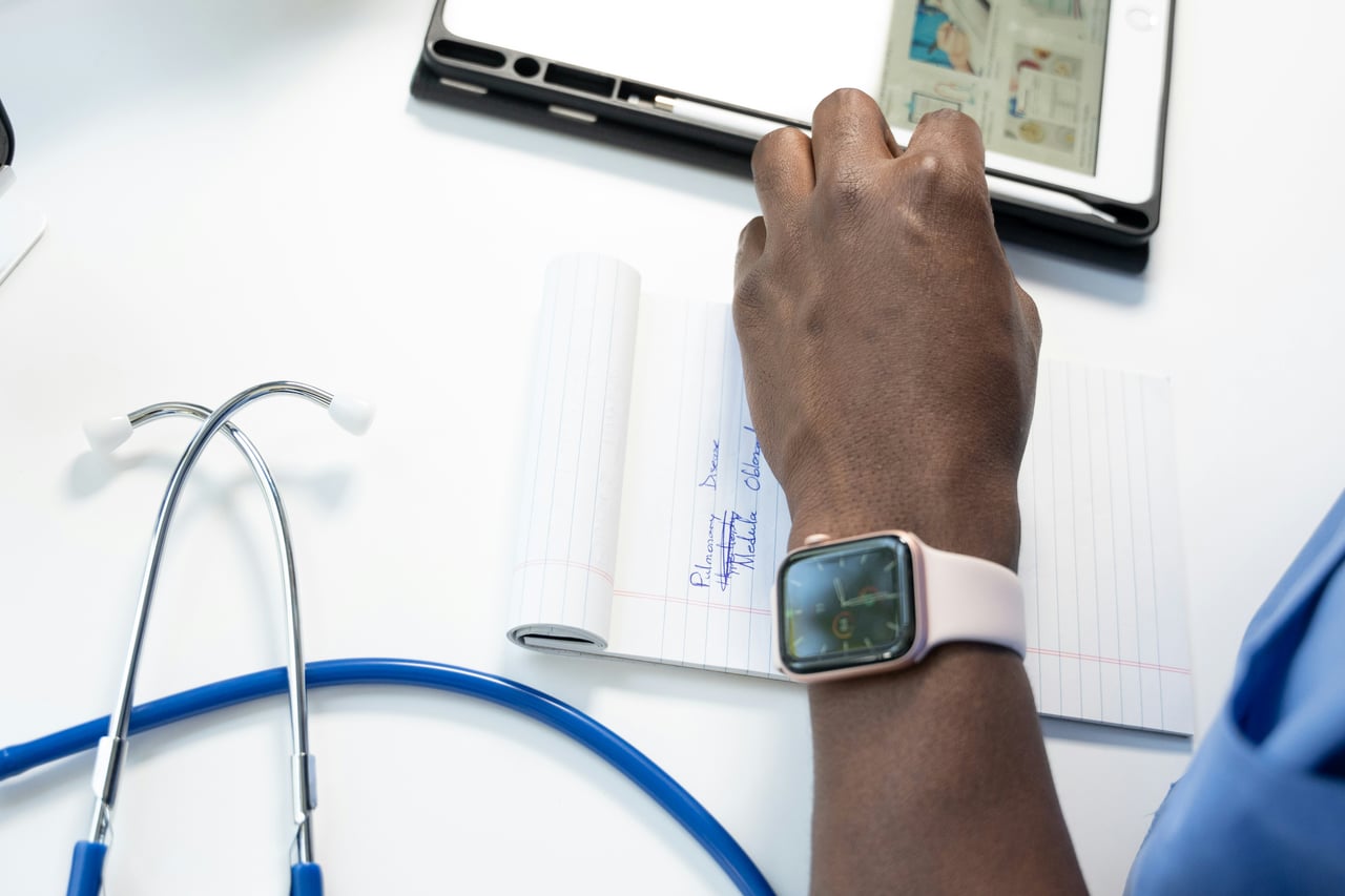 Clinician writing notes beside a stethoscope