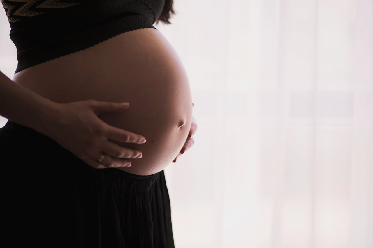 Pregnant woman resting her hands on her belly