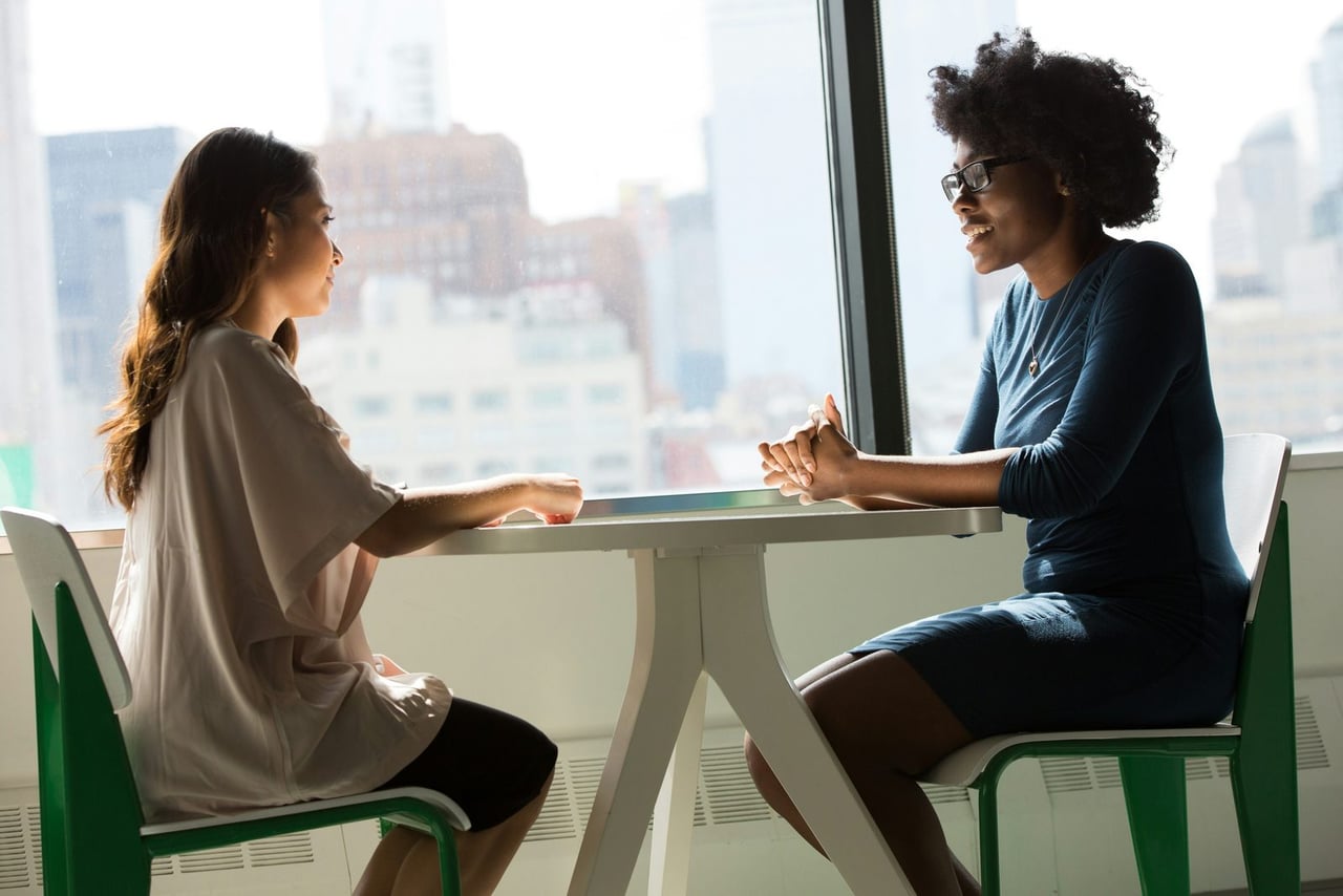 A dietitian and a client talking at a table by a window